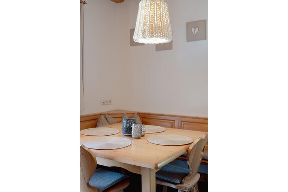 A cozy wooden dining table with four chairs and round placemats. The decorative lamp provides pleasant light in a bright room. - Chalet Carla - Umhausen