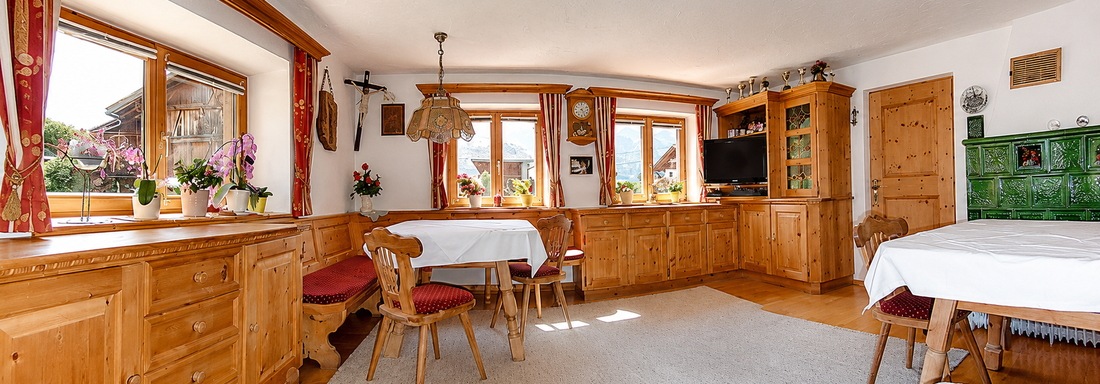 A cozy room with wooden furniture and many windows. The decor is warm and inviting, ideal for friendly gatherings. - Ferienhaus am Spielroan - Umhausen
