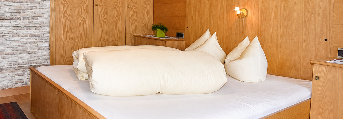 A modern bedroom with a large bed and soft pillows. The walls are made of wood and there is a cozy atmosphere. - Ferienhaus am Spielroan - Umhausen
