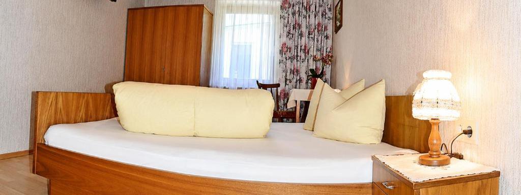 A cozy bedroom with a round bed and a bedside table. The room is bright and cheerful, with floral curtains and a television on the wall. - Ferienhaus am Spielroan - Umhausen