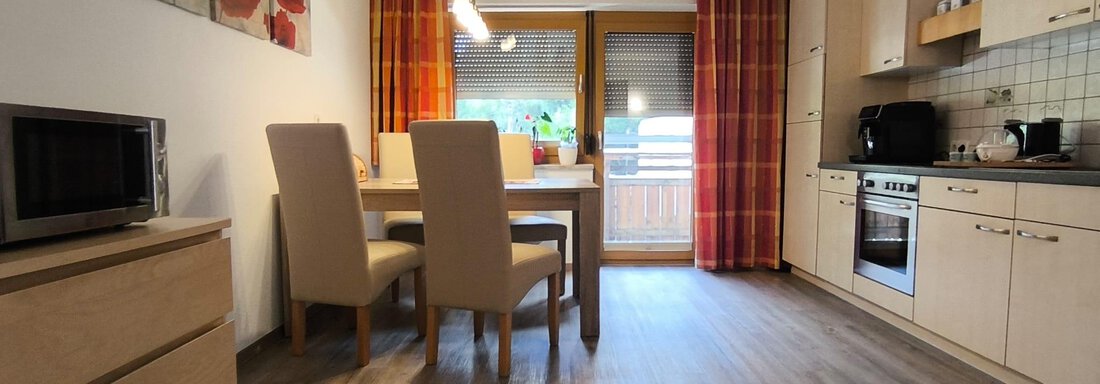 A modern kitchen with a dining area and bright furniture. Large windows let in plenty of light and create a pleasant atmosphere. - Ferienwohnung Martha - Umhausen