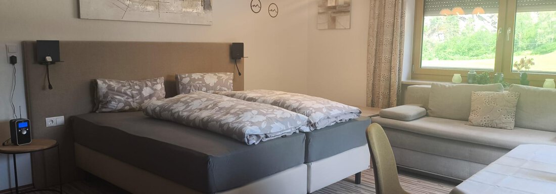 A modern room with two beds and a cozy sofa.  
Large windows bring in plenty of daylight. - Ferienwohnung Martha - Umhausen