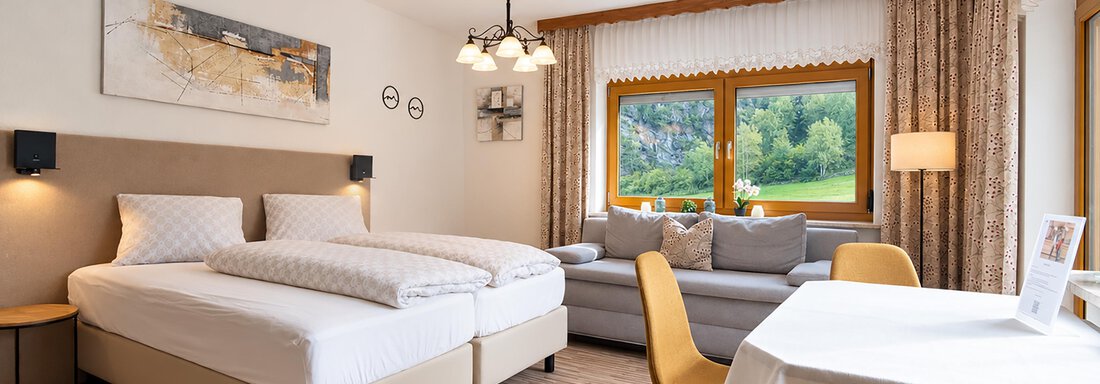 neue fotos_2 | © Belvilla (CC C) A cozy room with two beds, a sofa, and a table. Large windows provide a beautiful view of the surrounding nature. - Ferienwohnung Martha - Umhausen
