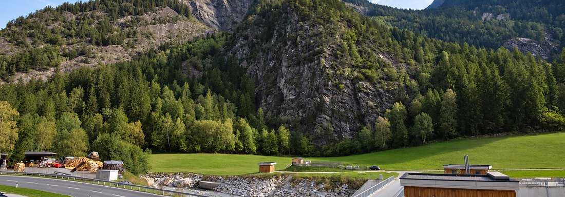 A green valley with an impressive mountain in the background. The surroundings are surrounded by dense forests and the road winds through the landscape. - Ferienwohnung Martha - Umhausen