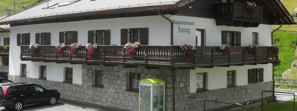A cozy holiday home with balconies and flower boxes. It is located in a green environment with cars and a bus stop nearby. - Appt. Garni Anny - Vent