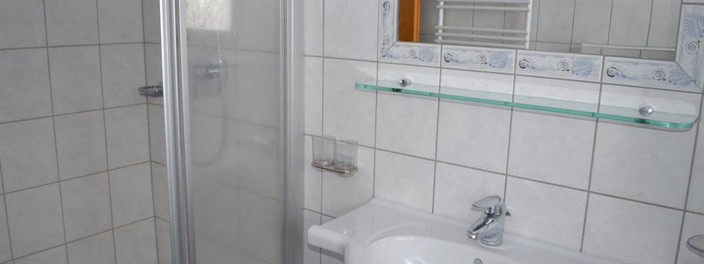 A modern bathroom with a shower cabin and a sink. The walls are tiled with light tiles. - Appt. Garni Anny - Vent