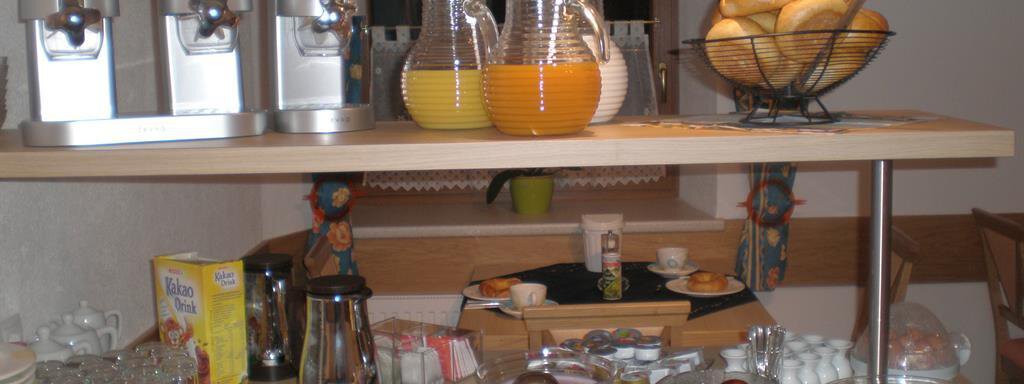 A breakfast buffet with various cereals, fresh rolls, and drinks in jugs. Additionally, cold cuts, cheese, and fresh fruit can be seen on the table. - Appt. Garni Anny - Vent