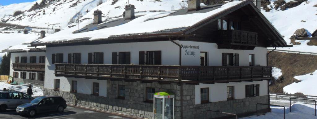 A traditional chalet in the mountains, surrounded by snow. There is a parking lot and a tranquil alpine landscape in the background. - Appt. Garni Anny - Vent