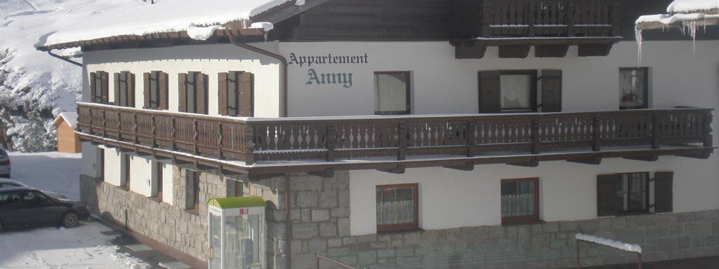 A charming apartment building in the snow, surrounded by an impressive mountain landscape. The facade features traditional alpine architecture. - Appt. Garni Anny - Vent