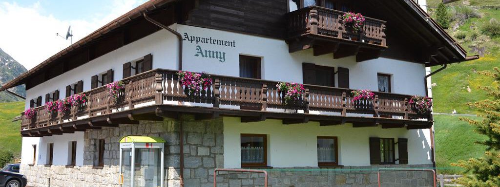 A charming house named "Appartement Amy." The facade is adorned with flower boxes and is set in a green environment. - Appt. Garni Anny - Vent