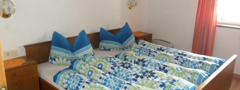 A cozy bedroom with a double bed and colorful bedspreads. The walls are bright, and a window lets in daylight. - Appt. Garni Anny - Vent