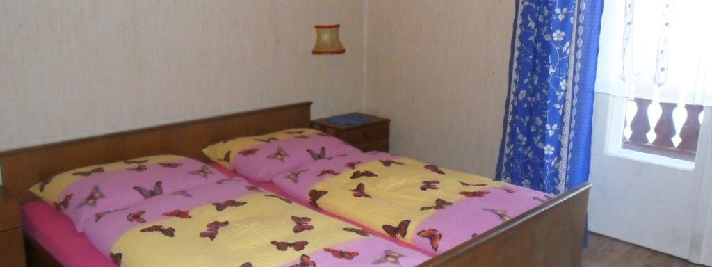 A cozy bedroom with a double bed and colorful bedspreads. The room has a bright atmosphere due to the window and the blue curtains. - Appt. Garni Anny - Vent
