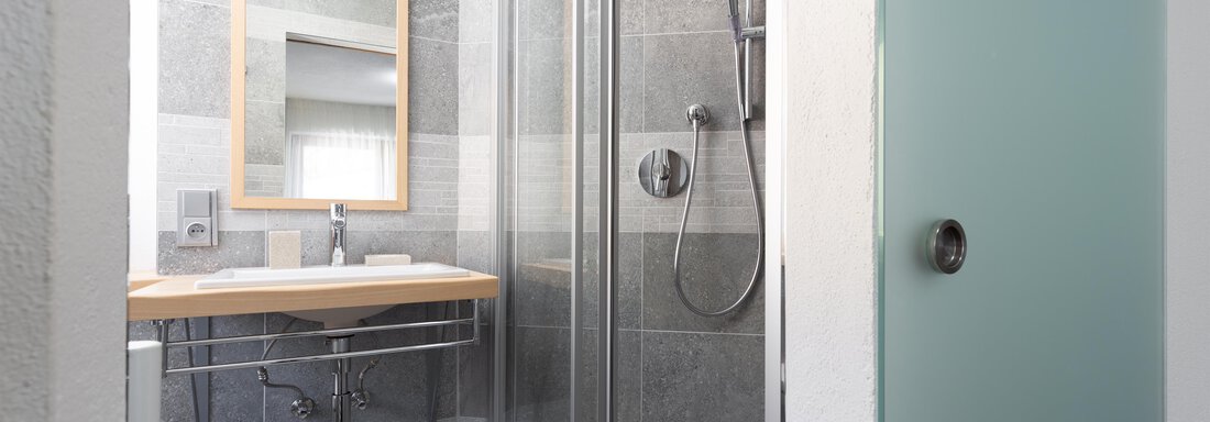 A modern bathroom with a glass shower and a wooden table. The space is designed in neutral colors and has a contemporary design. - Garni Stefani - Vent