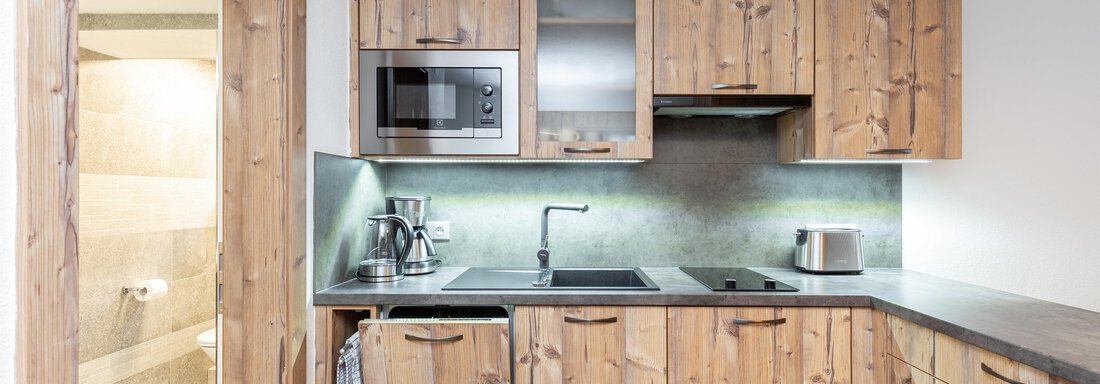 A modern kitchen with wooden cabinets and stainless steel appliances. It provides a bright and inviting space for cooking. - Garni Stefani - Vent