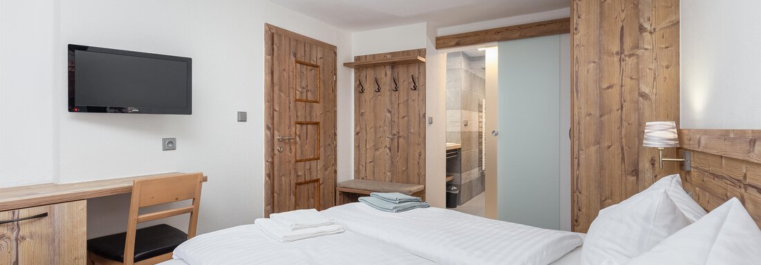A modern bedroom with a double bed and wooden furniture. The room is bright and cozy, equipped with a television and a desk. - Garni Stefani - Vent