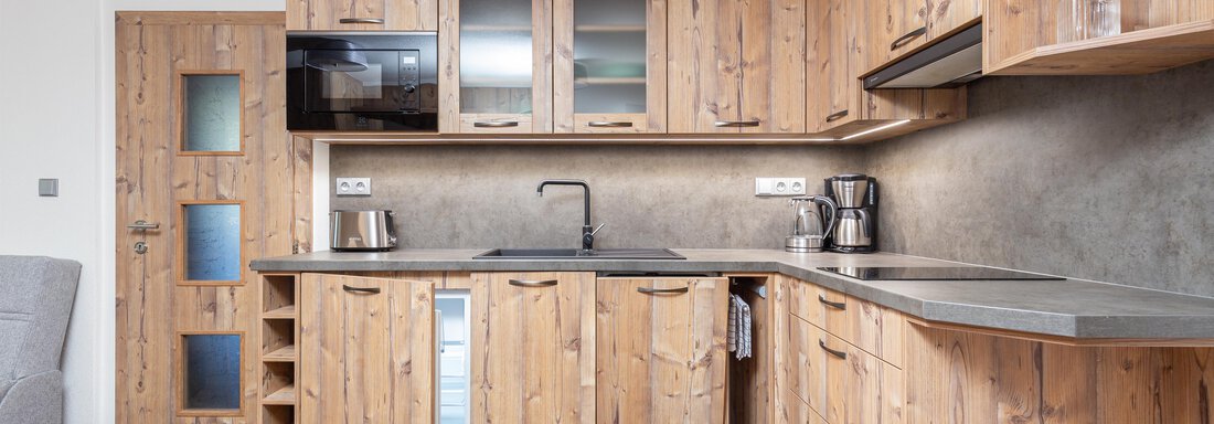 A modern kitchen made of wood with gray countertops and high-quality appliances. The space is friendly and well-lit. - Garni Stefani - Vent