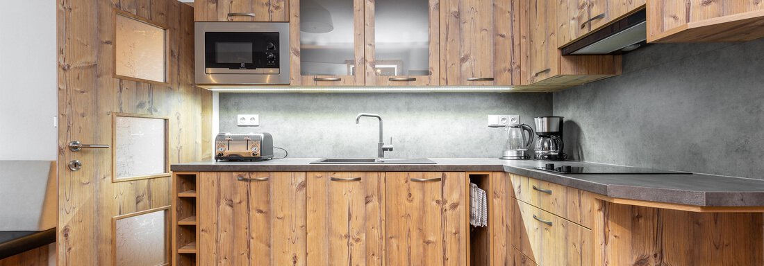 A modern kitchen made of wood with clean lines and elegant appliances. The atmosphere is warm and inviting. - Garni Stefani - Vent