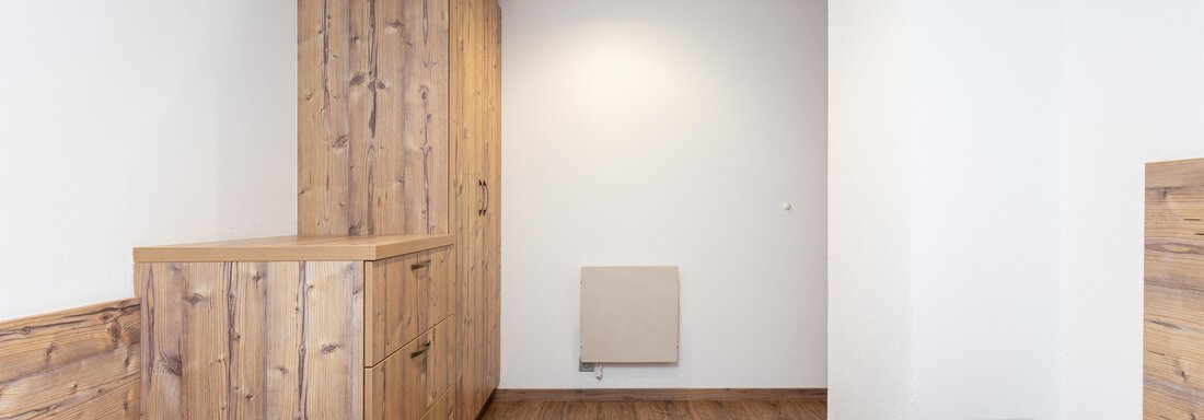 A modern bedroom with wooden details and a warm wooden floor. The beds are neatly made with white and blue bed linen. - Garni Stefani - Vent