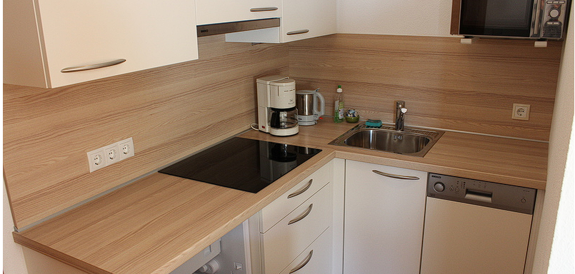Küchenblock A modern kitchen with bright cabinets and wooden surfaces. It is equipped with a refrigerator, a sink, and a coffee machine. - Gästehaus Soldanella - Vent