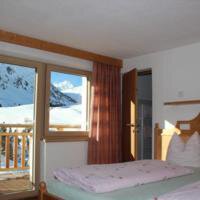A cozy bedroom with two beds and large windows. Outside, a beautiful mountain landscape can be seen. - Gästehaus Soldanella - Vent
