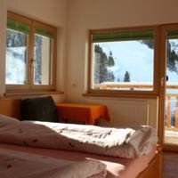 A cozy bedroom with a view of snow-covered mountains. The large windows allow plenty of natural light to enter. - Gästehaus Soldanella - Vent