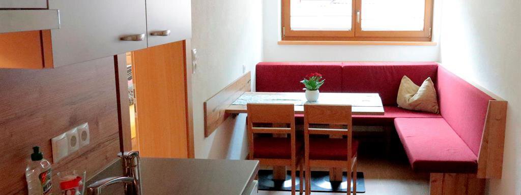 A small kitchen with a dining area. The room has a cozy seating area and plenty of daylight. - Gästehaus Soldanella - Vent