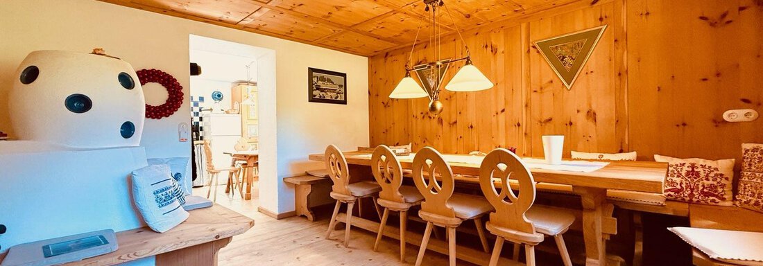 A cozy dining area with wooden paneling and a large table. The chairs have a unique design, and the lighting creates a warm atmosphere. - Haus Freistabl - Vent