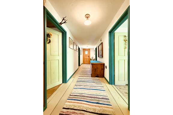 A bright hallway with colorful walls and a long carpet runner. Pictures hang on the walls and there are doors leading to various rooms. - Haus Freistabl - Vent