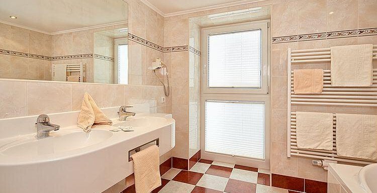 A modern bathroom with a large washbasin unit and a window. The tiles are designed in a classic black-white-red pattern. - Hotel Vent - Vent