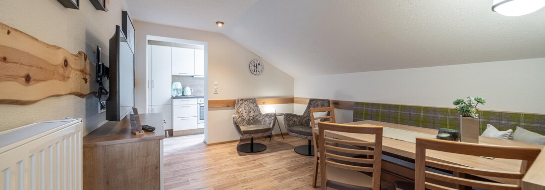 A bright, inviting living space with a table and chairs. The decor is modern and cozy, ideal for relaxing hours. - Garni Ötztal ROOMS & APARTS - Zwieselstein