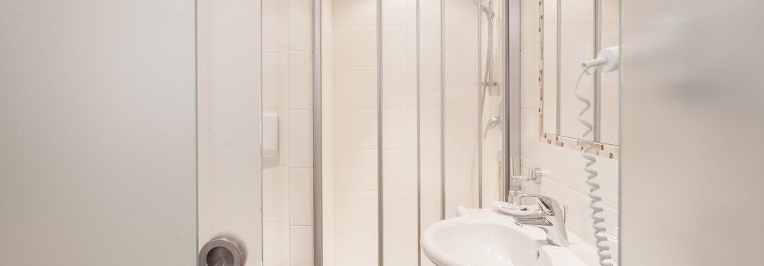 A modern bathroom with a shower and a sink. The walls are light, and the fittings are functional. - Garni Ötztal ROOMS & APARTS - Zwieselstein