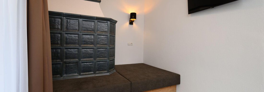 A modern room with a cozy seating area and a television on the wall. The room has light-colored walls and a beautiful flooring. - Gästehaus Judith - Zwieselstein