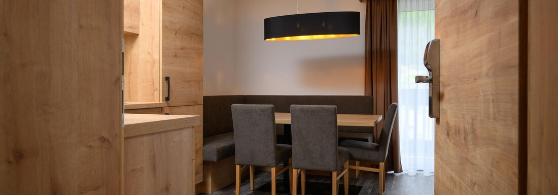 A modern dining room with wooden furniture and a large table. The cozy atmosphere is enhanced by the light and the windows. - Gästehaus Judith - Zwieselstein