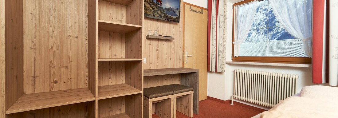 A modern room with wooden shelves and a desk. A window with a view of the mountains provides plenty of daylight. - Gästehaus Judith - Zwieselstein
