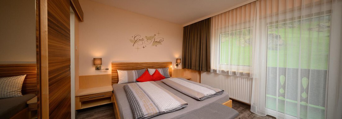 A modern bedroom with a large bed and bright wood design.  
Large windows provide plenty of light and a pleasant atmosphere. - Haus Sonnschein - Zwieselstein