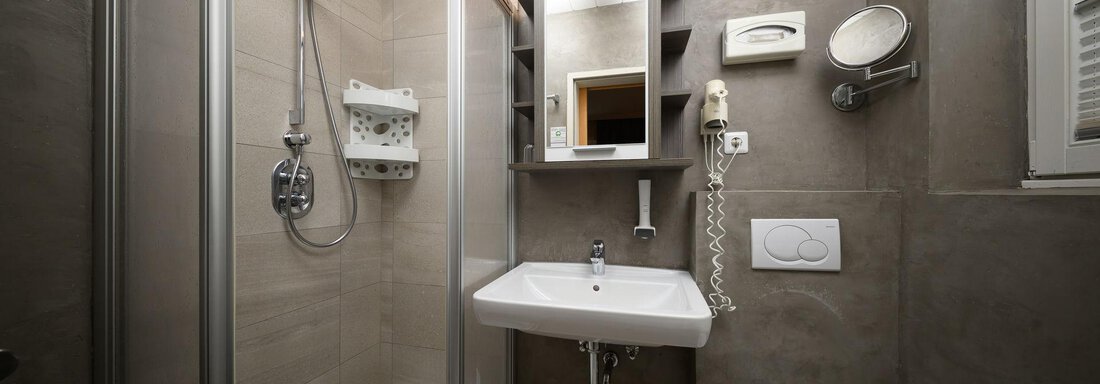 A modern bathroom with a glass shower and a sink. The walls are in a neutral gray and there is ample lighting. - Haus Sonnschein - Zwieselstein