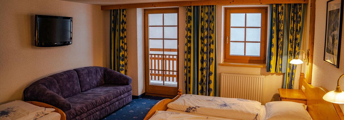 A cozy hotel room with a double bed and a sofa bed. Large windows provide plenty of daylight and a bright atmosphere. - Hotel Gasthof Zwieselstein - Zwieselstein