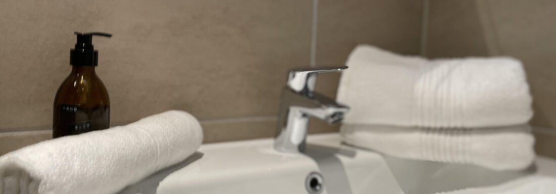 A modern sink with a soap dispenser and fresh towels. The room has a clean and inviting atmosphere. - International House Sölden - Zwieselstein