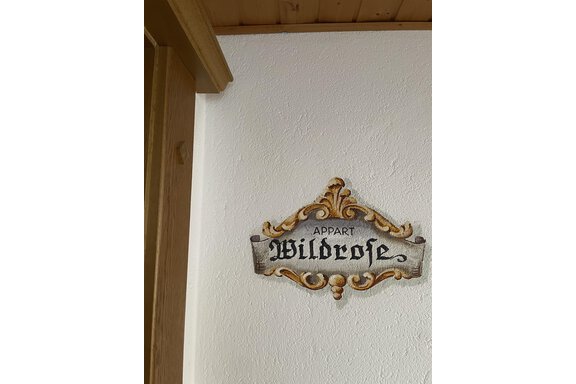 A decorative sign reading "APPART WILDEROSE" on a white wall. The sign features golden and silver details. - Landhaus Rosenhof - Zwieselstein